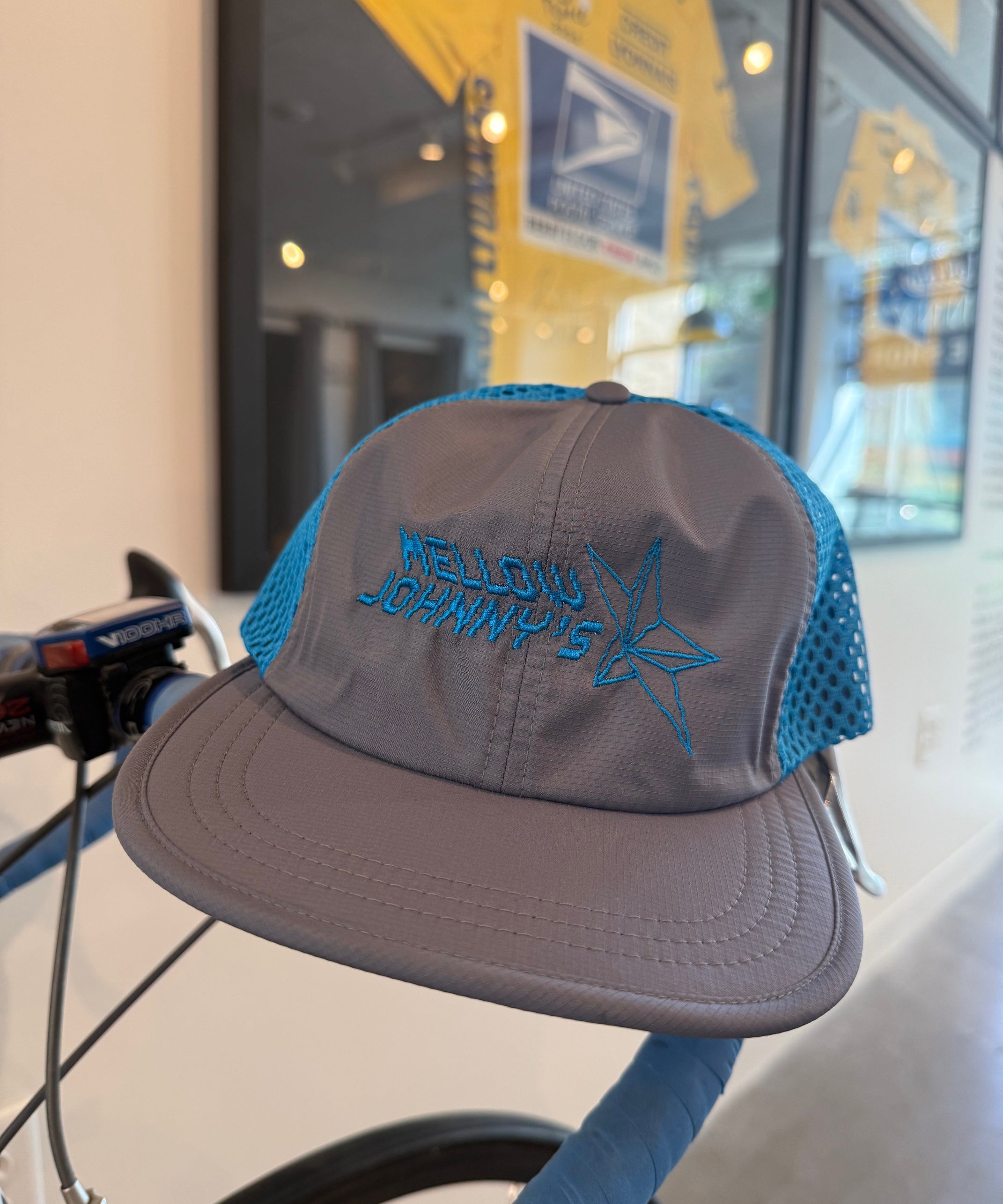 Gray cap with blue brim and embroidered logo on a bicycle