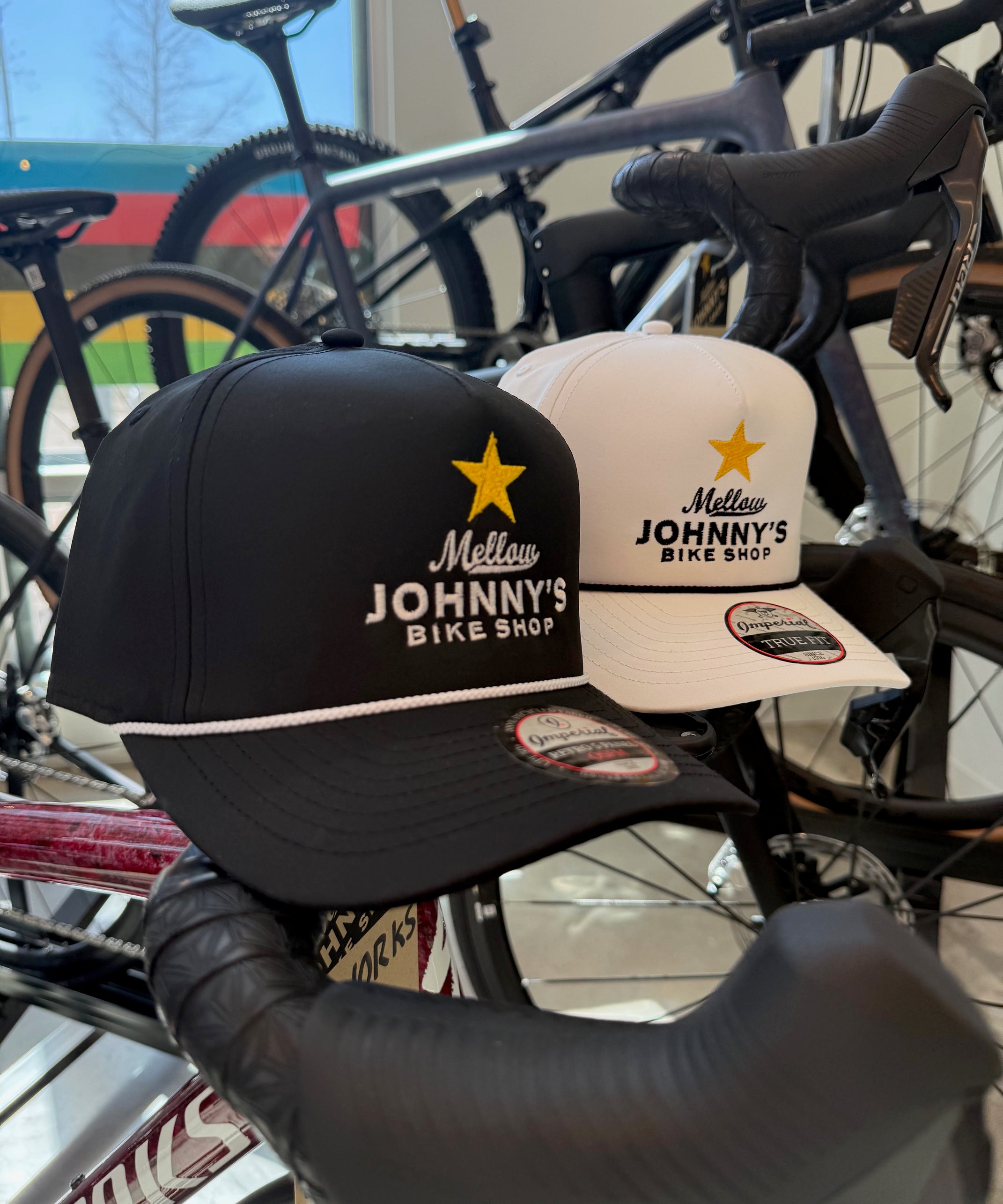 Two caps with 'Mellow Johnny's Bike Shop' branding on a bicycle handlebar.