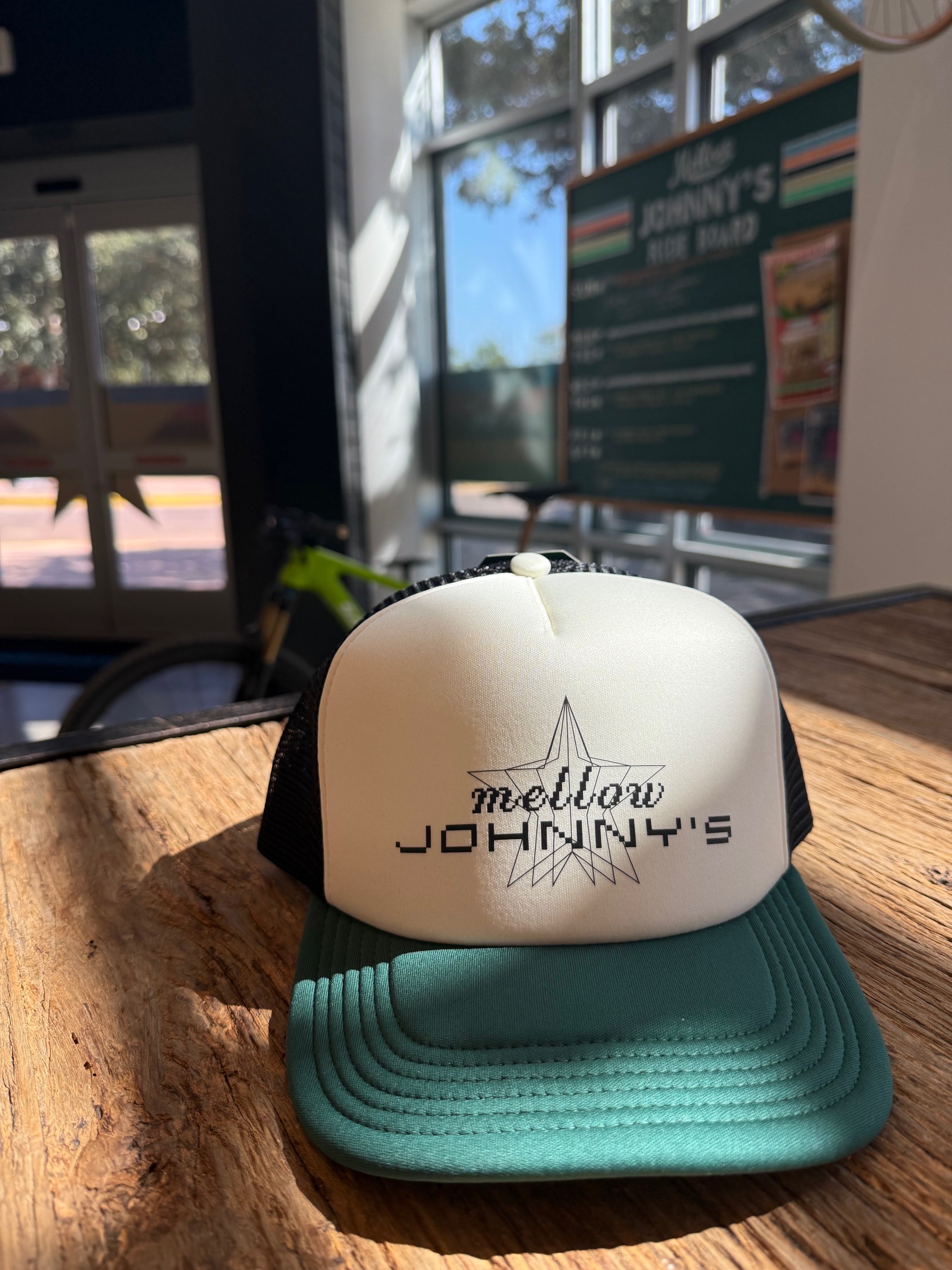 Green and white hat with 'Mellow Johnny's' text on a wooden surface